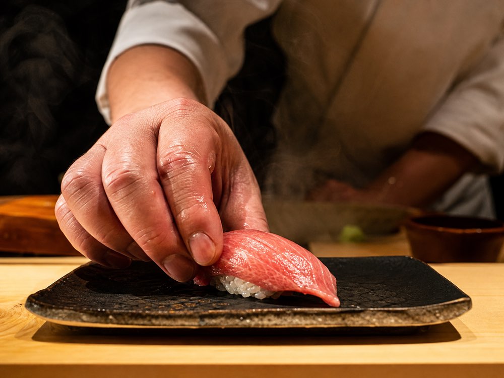 職人の手元から差し出される一貫の握り（イメージ）